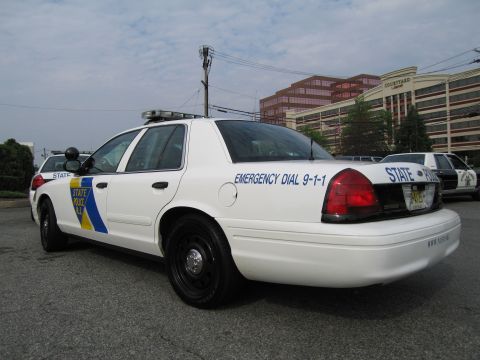 1991 Ford LTD Crown Victoria - Rear three-quarter view of a white New Jersey State Police Ford Crown Victoria with Emergency Dial 9-1-1 lettering, parked near office buil…