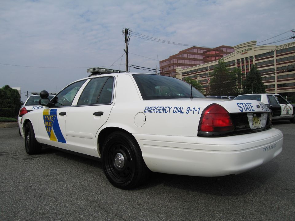 Rear three-quarter of white NJ State Police Crown Victoria reading Emergency Dial 9-1-1
