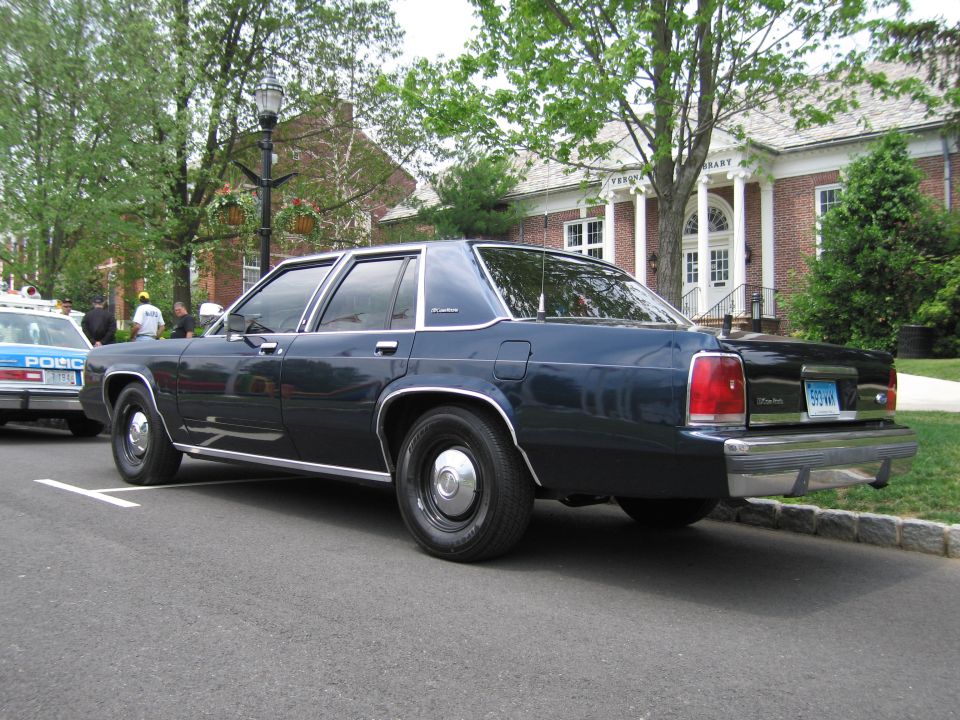 Dark blue Ford LTD Crown Victoria sedan rear three-quarter at curb by brick building