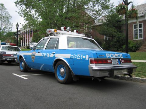1991 Ford LTD Crown Victoria - blue-and-white NYPD Highway Patrol Dodge sedan, car 2840, parked at a curb with roof light bar, shown from the rear three-quarter.