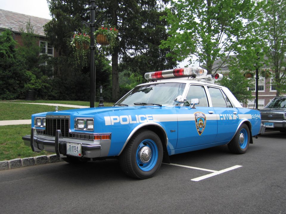 Blue and white NYPD Highway Dodge police car, front three-quarter at curb