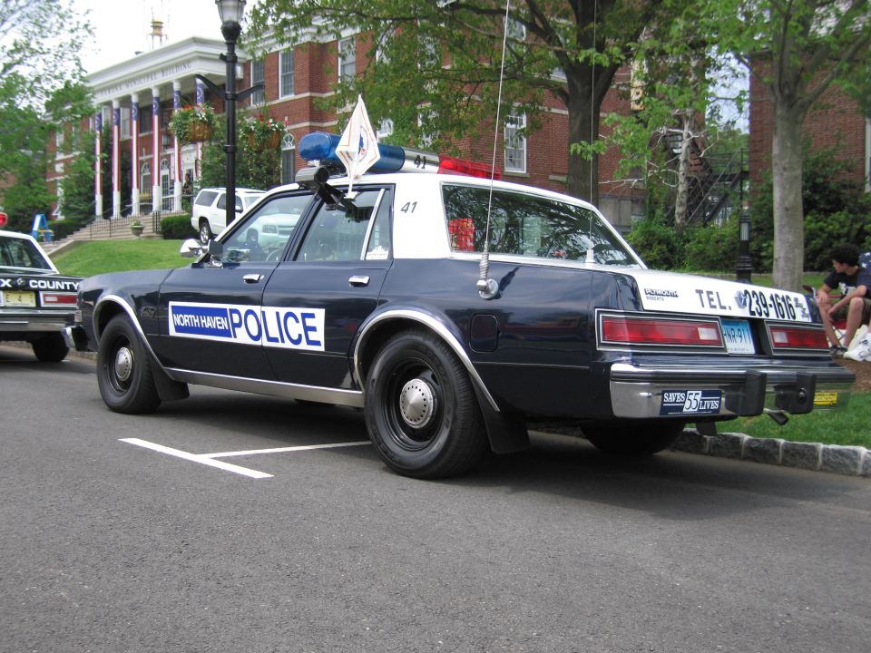 Dark blue North Haven Police Dodge sedan parked at curb, rear three-quarter