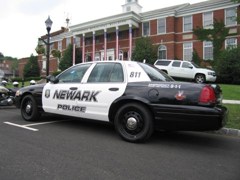 1991 Ford LTD Crown Victoria - black-and-white Newark Police Ford Crown Victoria numbered 811 parked rear three-quarter outside a flag-draped municipal building.