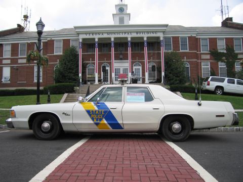 1991 Ford LTD Crown Victoria - Driver-side profile of a white NJ State Police Dodge sedan parked in front of the Verona Municipal Building.