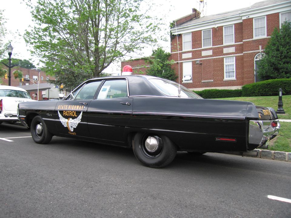 Black Ohio State Highway Patrol sedan with gold winged emblem, rear three-quarter view