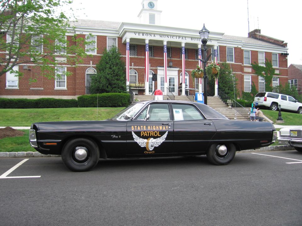 Black Ohio State Highway Patrol Plymouth Fury, driver-side profile, before municipal building