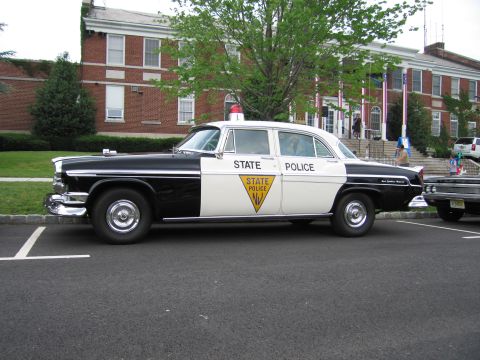 1991 Ford LTD Crown Victoria - 1950s black-and-white New Jersey State Police Chrysler sedan shown front three-quarter before a brick municipal building.