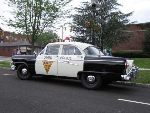 1991 Ford LTD Crown Victoria - 1950s black-and-white New Jersey State Police Ford sedan shown front three-quarter with a single red roof beacon.
