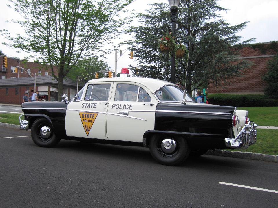 1950s black and white NJ State Police Ford sedan, front three-quarter, single roof beacon