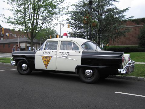 1991 Ford LTD Crown Victoria - Front three-quarter view of a 1950s black-and-white New Jersey State Police Ford sedan parked at a curb.