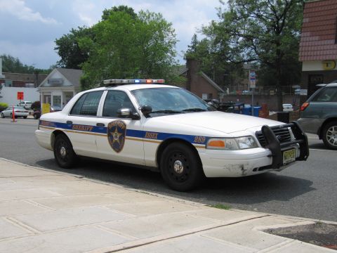1991 Ford LTD Crown Victoria - White Essex Sheriff Ford Crown Victoria unit 289 fitted with a push bar, shown front three-quarter on a town street.