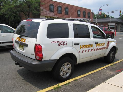 1991 Ford LTD Crown Victoria - Rear view of a white Verona Police Dodge Durango SUV reading Emergency 9-1-1, parked on a town street.