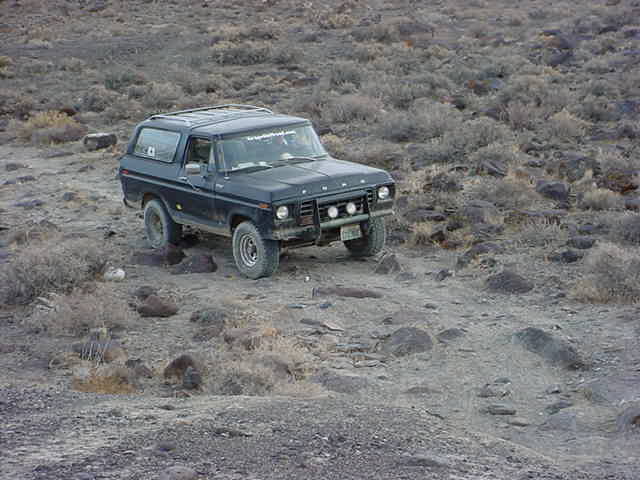 Distant blurry vehicle driving across a dirt or sand area