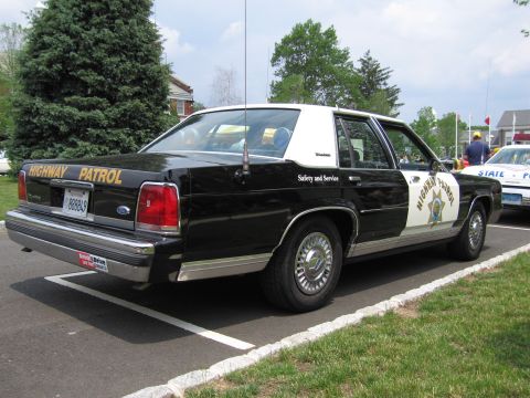 1991 Ford LTD Crown Victoria - Rear view of a black-and-white Ford Highway Patrol sedan with a gold star shield on the door.