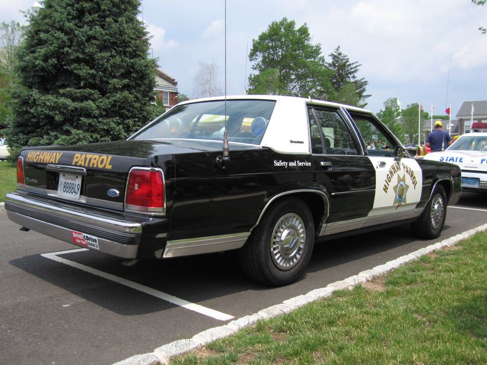Rear of black-and-white Ford Highway Patrol sedan with star door shield