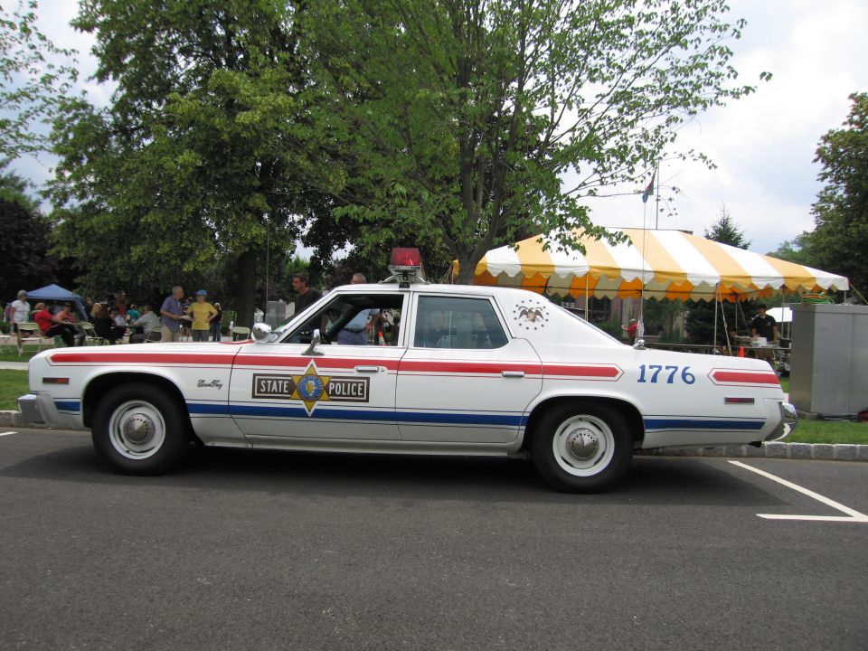 White State Police sedan #1776 in profile near event tents