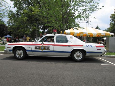 1991 Ford LTD Crown Victoria - Side view of a white State Police sedan numbered 1776 with a star shield on the door and roof light.