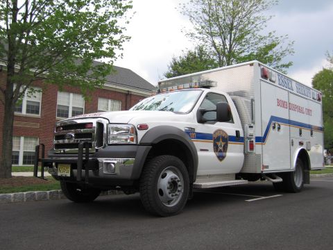 1991 Ford LTD Crown Victoria - Front three-quarter view of a white Ford Essex Sheriff Bomb Disposal Unit truck with a grille guard, parked by a brick building.