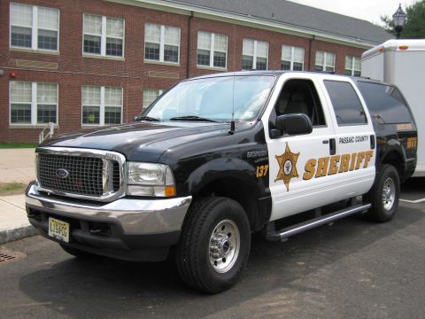 1991 Ford LTD Crown Victoria - Front three-quarter view of a black-and-white Passaic County Sheriff Ford Excursion SUV with chrome grille, parked by a brick building.