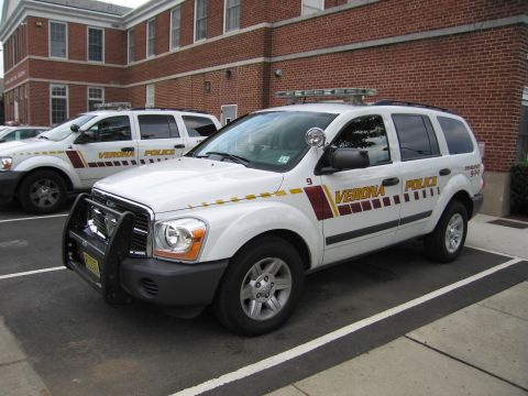 1991 Ford LTD Crown Victoria - white Verona Police Dodge Durango SUV with push bar and roof lights, parked beside another police SUV.
