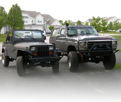 1991 Jeep Wrangler - Two modified SUVs, a Jeep Wrangler and a Ford Bronco, are parked next to each other.