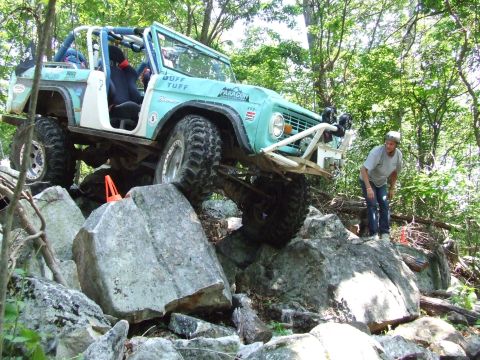1967 Ford Bronco - This modified Bronco is navigating a challenging rocky trail with a spotter nearby.