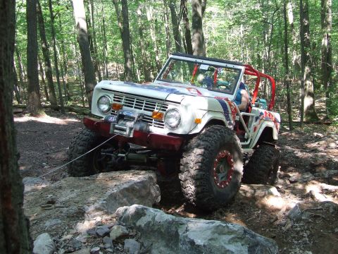 1967 Ford Bronco - This 1967 Ford Bronco is tackling a challenging off-road course with large tires and a winch.