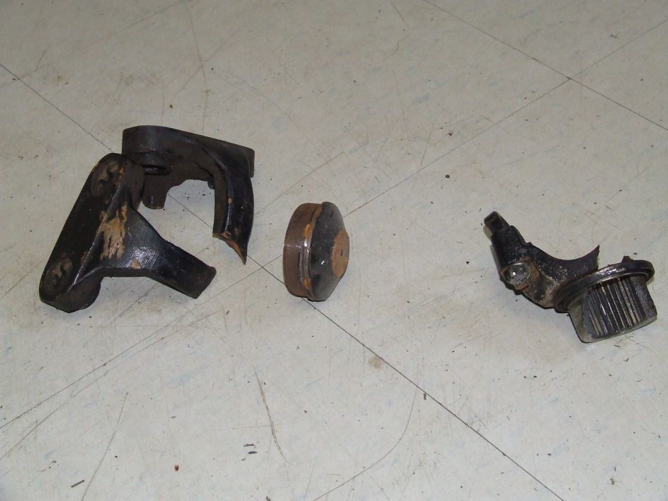Broken engine parts on a white surface. Includes a cracked bracket and a ribbed component
