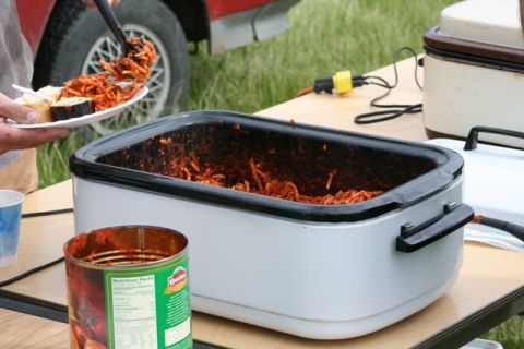 1990 Chevrolet Suburban - Spaghetti is served from a crockpot next to a red vehicle at an outdoor gathering.