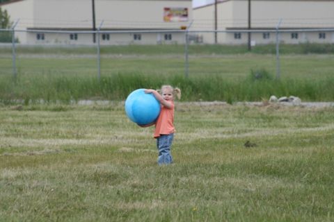 1990 Chevrolet Suburban - A young child stands in a field holding a large blue ball.