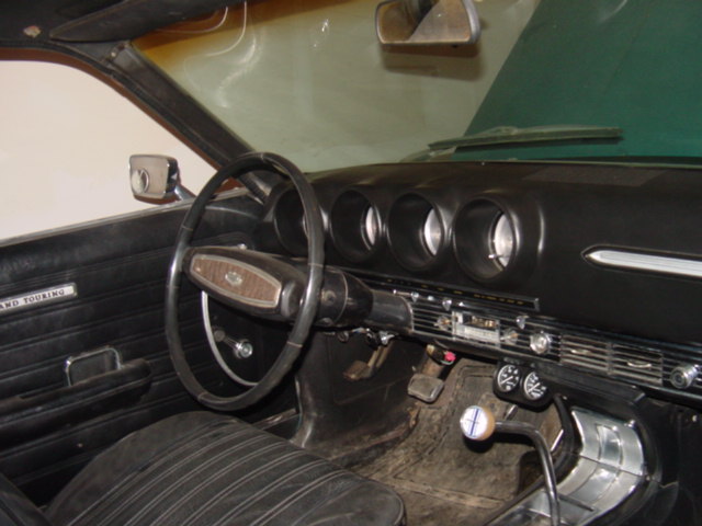 Interior of vintage car showing two-spoke steering wheel and round-pod dashboard