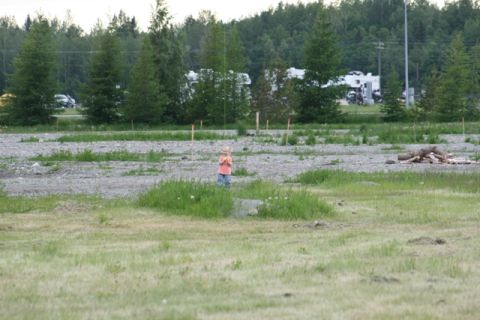 1990 Chevrolet Suburban - A child stands in a grassy area with RVs and other vehicles visible in the distance.