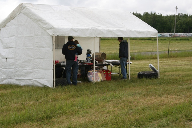 White tent with people and tables set up on grassy field