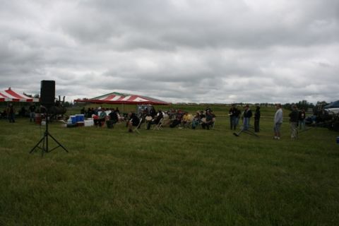 1990 Chevrolet Suburban - An outdoor event takes place under a cloudy sky, with attendees gathered near tents and a sound system.