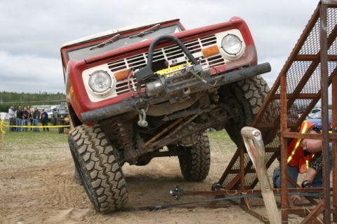 1990 Chevrolet Suburban - First-generation Ford Bronco navigates a challenging obstacle during an event.
