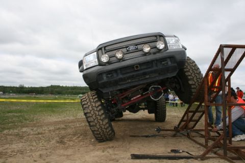 1990 Chevrolet Suburban - Modified Ford Super Duty truck navigating an off-road obstacle course with a tilted stance.
