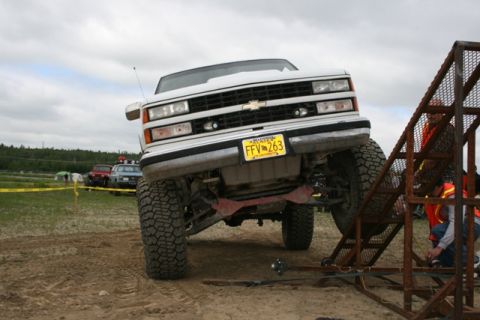 1990 Chevrolet Suburban - A white Chevrolet pickup truck is positioned on a dirt ramp with other vehicles in the background.