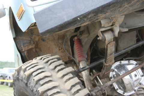 1990 Chevrolet Suburban - This photo shows the suspension and tire of a vehicle, with other vehicles in the background.