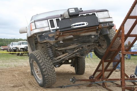 1990 Chevrolet Suburban - A modified Jeep Grand Cherokee is positioned on a metal ramp during an off-road event.