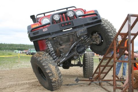1990 Chevrolet Suburban - A red Jeep Wrangler with oversized tires navigates a challenging obstacle course, demonstrating its off-road capabilities.