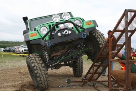 1990 Chevrolet Suburban - A green Jeep Wrangler navigates an off-road obstacle course, demonstrating its capabilities with a winch and snorkel.