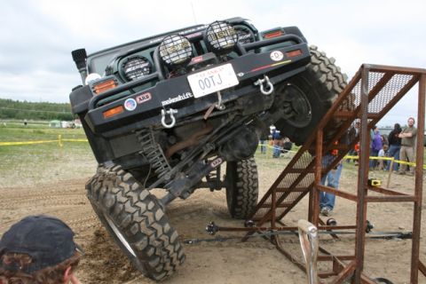 1990 Chevrolet Suburban - Off-road vehicle navigating a challenging obstacle course with a metal ramp.