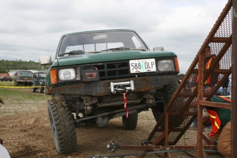 1990 Chevrolet Suburban - A green pickup truck is parked on a dirt surface, with a winch mounted on its front bumper.