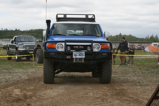 Blue Toyota FJ Cruiser with snorkel and roof rack, facing forward. Another truck is parked behind it