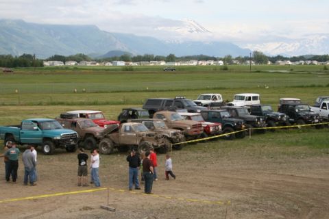 1990 Chevrolet Suburban - A collection of modified off-road vehicles are gathered in an outdoor event space.