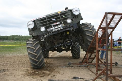 1990 Chevrolet Suburban - A modified monster truck with oversized tires is positioned on a dirt track.