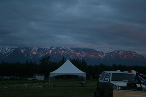 1990 Chevrolet Suburban - An SUV is parked in a field with a tent and mountains in the background during twilight.