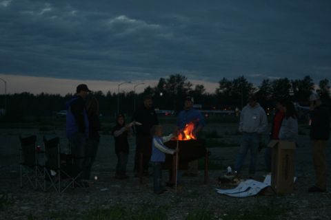 1990 Chevrolet Suburban - A group of people enjoy a fire pit gathering as dusk settles in.