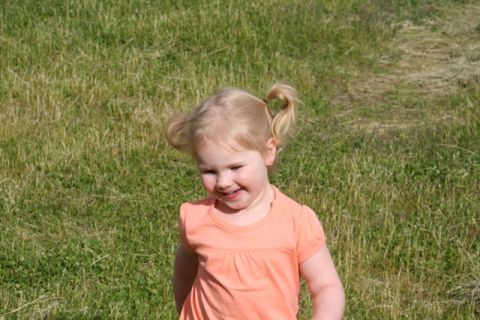1990 Chevrolet Suburban - A young child with blonde hair in pigtails smiles while standing in a field of grass.