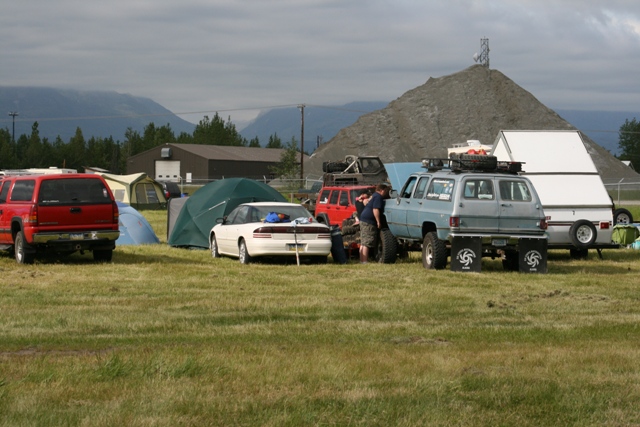 Light blue 1990 Chevrolet Suburban with roof rack and lifted suspension, parked on grass